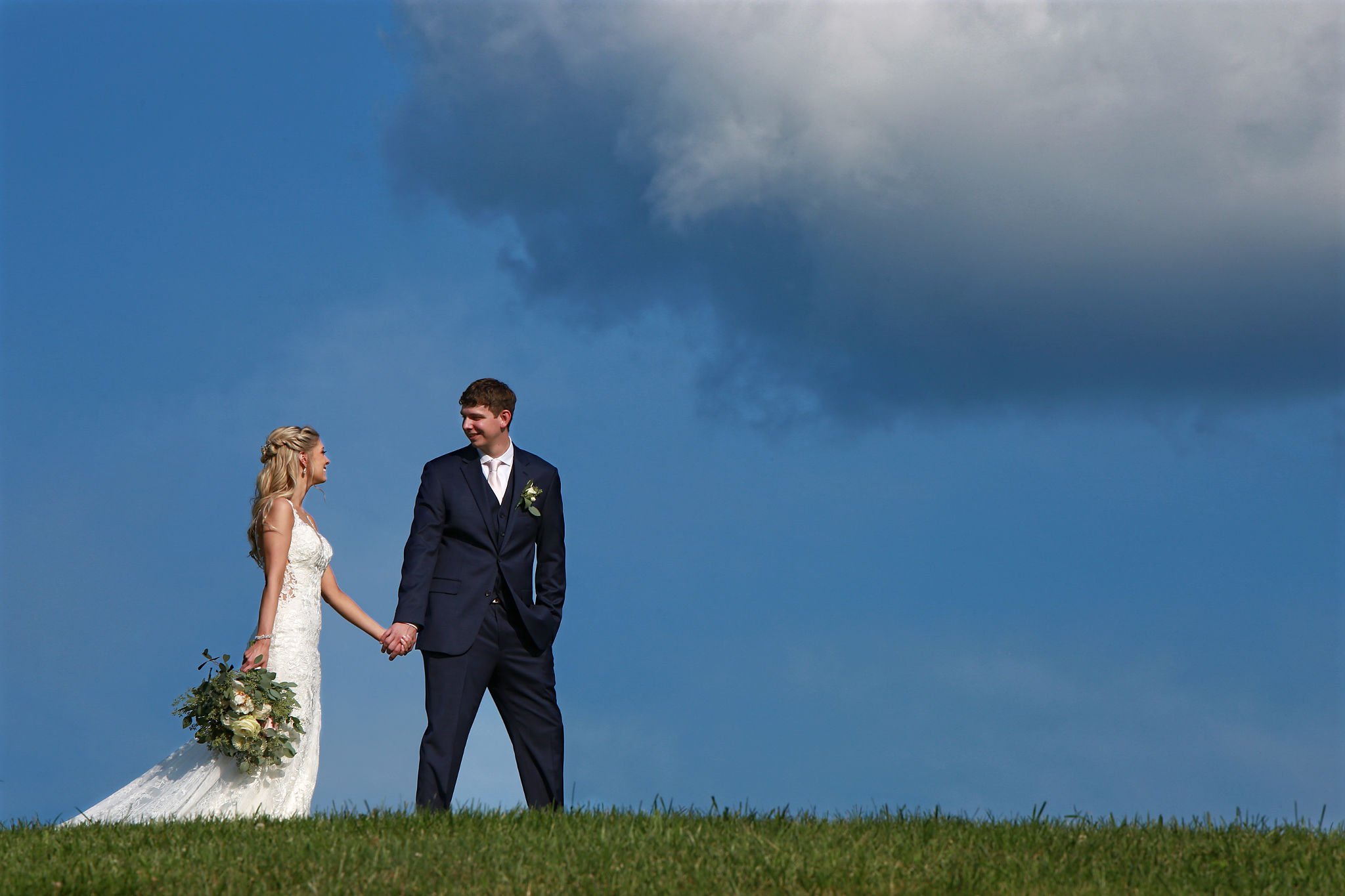 Bride and groom walking under dramatic sky